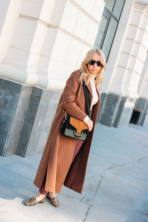 Stijlvolle blonde vrouw met lange bruine mantel winterjassen trend
